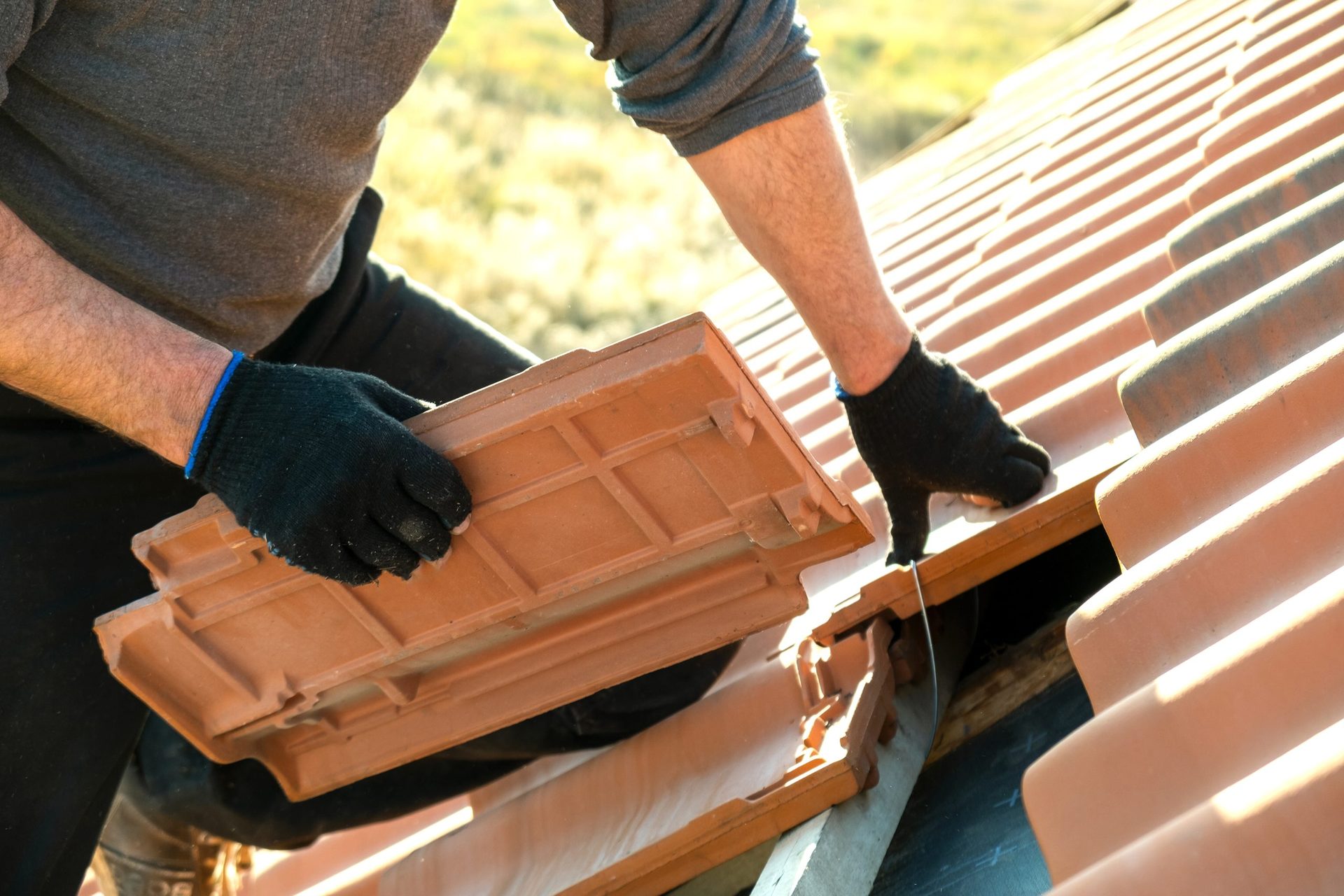 Roofer installing ceramic roof tiles on timber battens