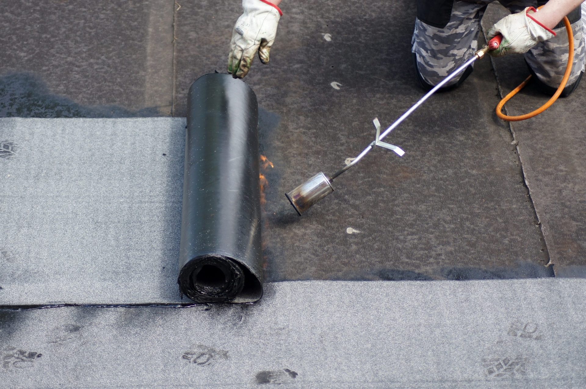 Roofer applying bitumen roofing felt with blow torch Roofer applying bitumen roofing felt with a blow torch