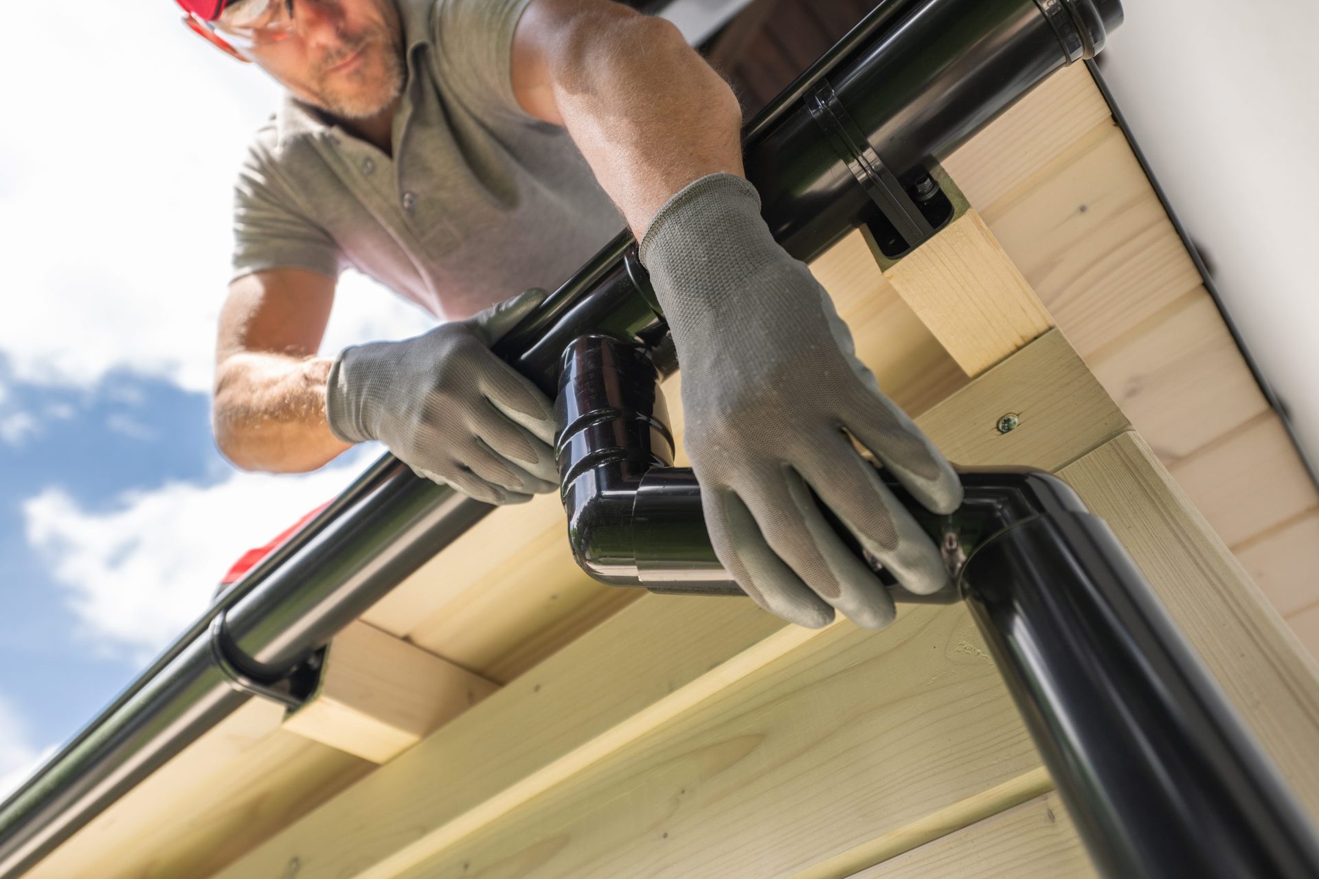 Roofer installing a gutter downpipe on a house